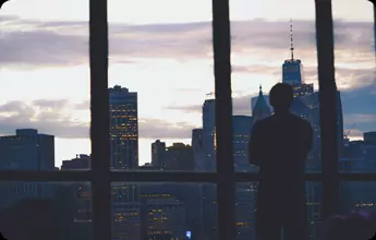 a businessman looks out the window of his building

